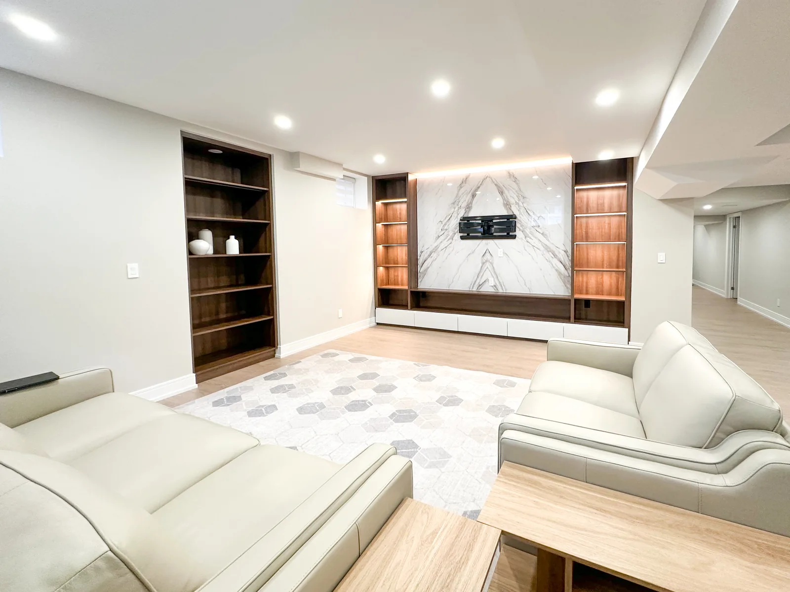 A finished basement living room renovation with custom built-ins and a marble feature wall
