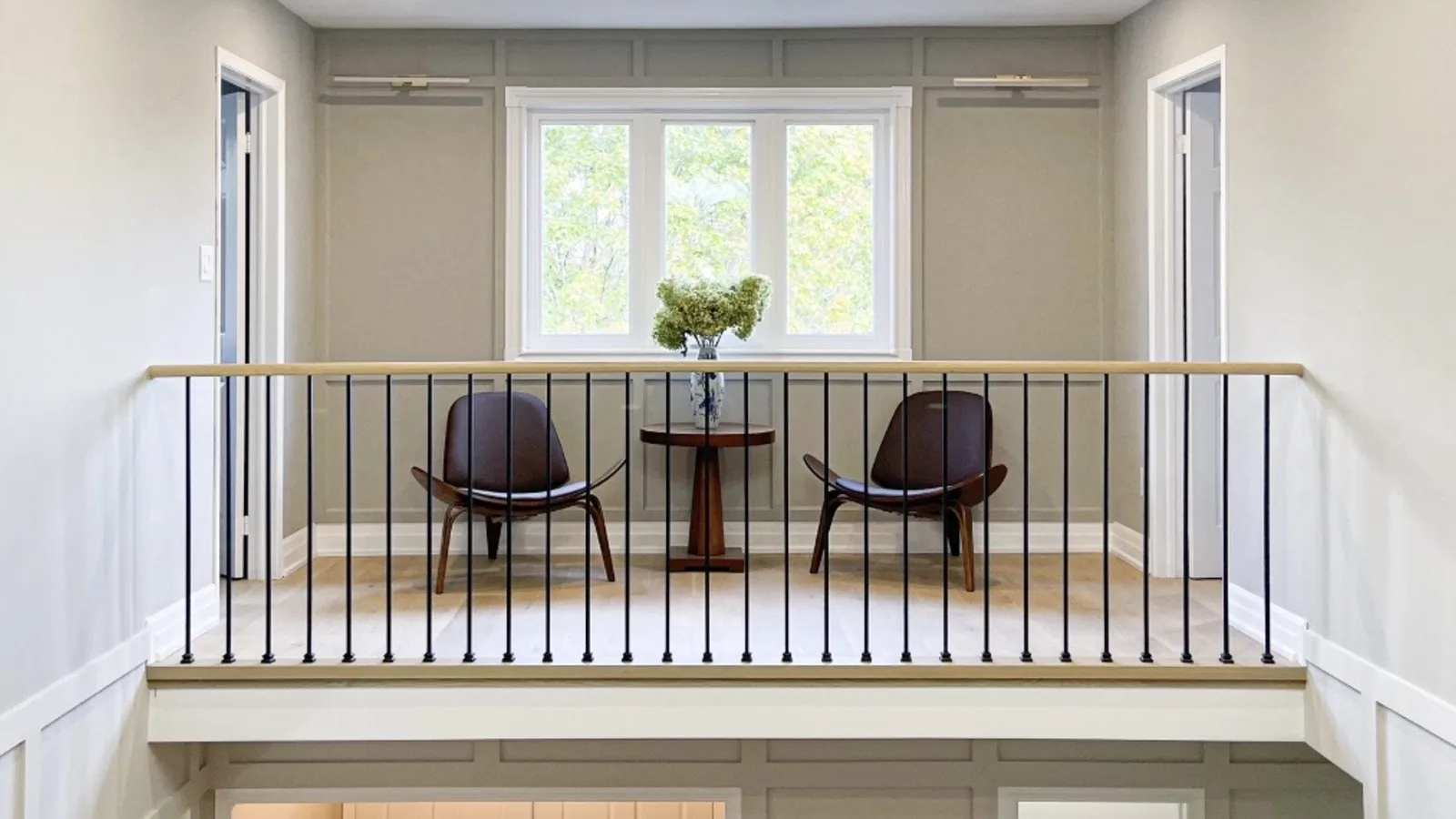 Renovated upstairs landing with new hardwood flooring, wainscoting, and a custom railing